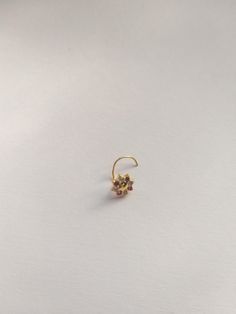 a gold ring with two small flowers on it's side, sitting on a white surface