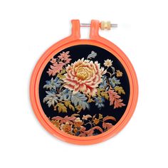 an orange and black round case with floral designs on it, hanging from a hook