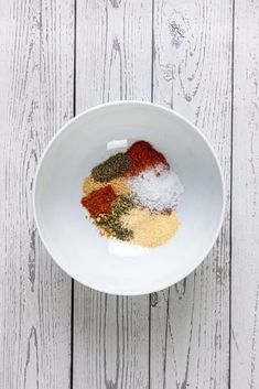 a white bowl filled with spices on top of a wooden table