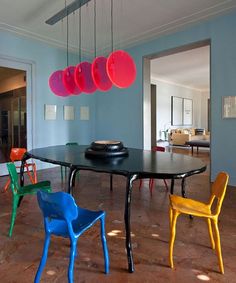 a dining room table with four chairs and five lights hanging from it's ceiling