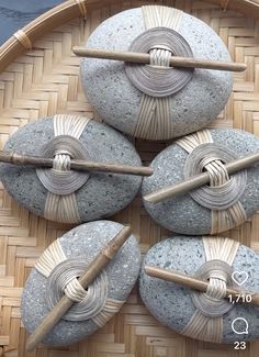 four rocks with knitting needles on them sitting in a woven basket next to two balls of yarn