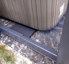 a metal object sitting on the ground next to a wooden structure with grass growing out of it