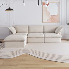 a white couch sitting on top of a hard wood floor next to a wall mounted painting