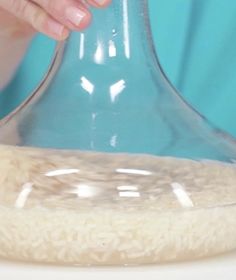 a person is pouring rice into a glass vase