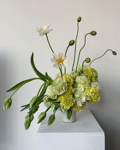 a white vase filled with green and white flowers