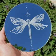 a hand holding up a blue plate with a white dragon on it's side