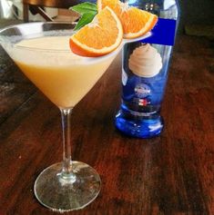 two orange slices sit on the rim of a cocktail glass next to an empty bottle