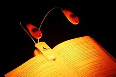 an open book with headphones attached to it's sides, lit up in the dark