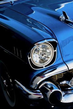 the front end of an old blue car with chrome rims and hood ornament