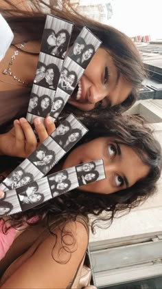 two young women are holding up pictures with faces on them