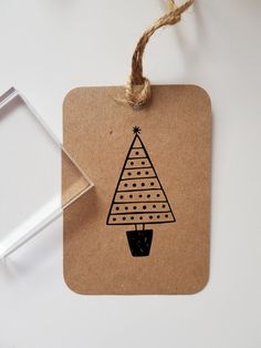 a tag with a christmas tree drawn on it next to a small glass container and some twine