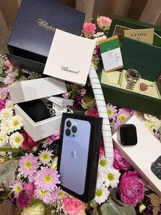 an assortment of cell phones in boxes on a table with pink and white flowers around them