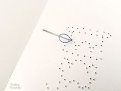 a pair of scissors and some beads on a white surface with holes in the middle