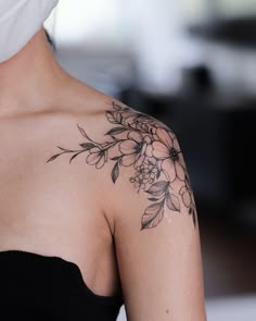 a woman's shoulder with flowers and leaves on it