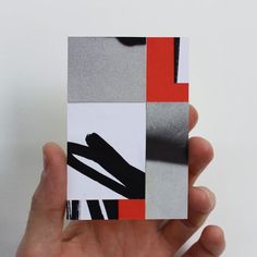 a hand holding up a piece of paper with black, white and red squares on it