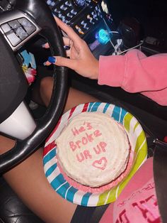 a woman is sitting behind the wheel of a car with a birthday cake in front of her