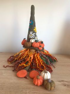 a small hat with many different types of yarn on it, sitting on top of a wooden table