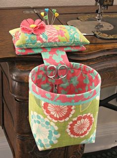 two purses sitting on top of a wooden table with sewing needles in the middle