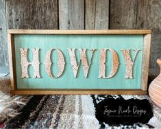 a wooden sign with the word hovdy painted on it and a vase next to it