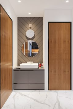 a modern bathroom with marble counter tops and wood paneling on the walls, along with an oval mirror