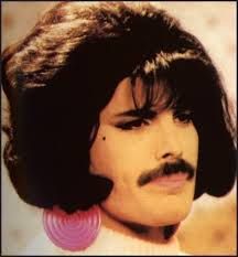 a man with a moustache on his face wearing large pink earrings