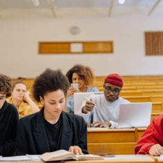 several students are sitting at desks in a lecture hall and one student is taking notes