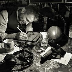 a man sitting at a table writing on a notebook