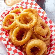 some onion rings are on a red and white checkered paper