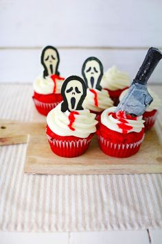 cupcakes with white frosting and spooky decorations on a cutting board