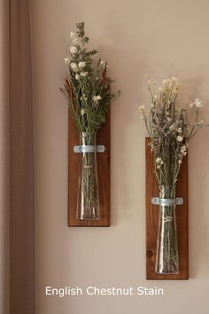 two vases with flowers are hanging on the wall