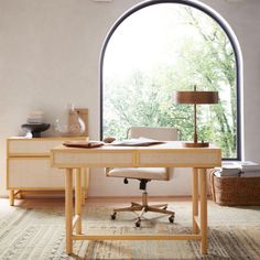 a desk with a chair and lamp in front of an arched window