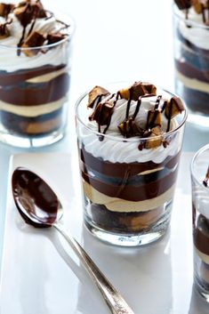 three desserts with chocolate and marshmallow toppings in small glasses on a table