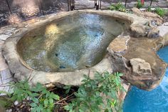 an outdoor hot tub surrounded by rocks and water