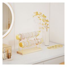 a vase with flowers on a white counter next to some candles and other items in front of a mirror