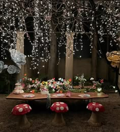 a table with mushrooms and flowers on it in the middle of a forest at night