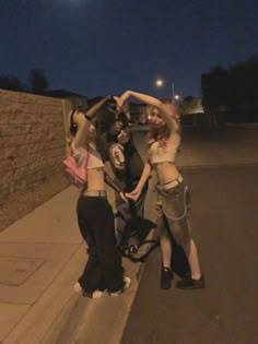 three young women standing on the side of a road with their arms in the air