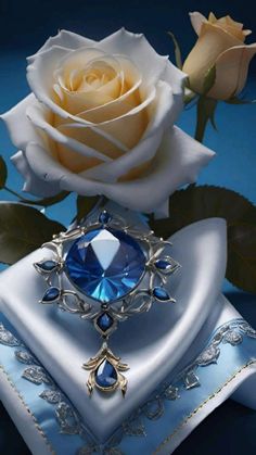 a white rose and blue jeweled brooch sitting on top of a satin pillow