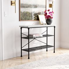 a black and white console table with pink flowers on it in front of a painting