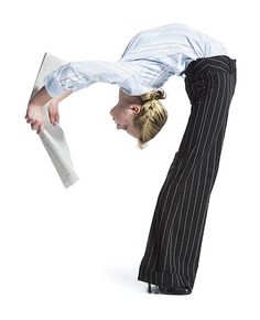 a woman is doing a handstand while holding papers