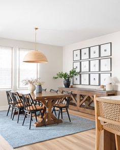 a dining room table with chairs and pictures on the wall