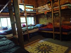 a room with bunk beds and rugs on the floor in front of two windows