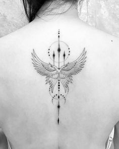 a woman's back with an arrow and wings tattoo