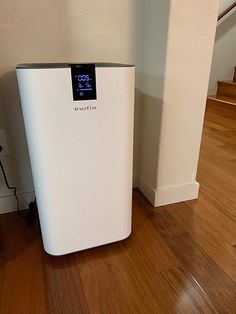 a white refrigerator sitting on top of a hard wood floor next to a stair case