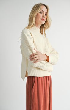 Stay warm and stylish in our Liss Turtleneck Sweater. This pullover features a thick, luxurious knit and a flattering mock neck design. The relaxed, slightly cropped fit is perfect for pairing with high-waisted pants. With cozy cable knit detailing and a slight high-low hem, this sweater offers both comfort and a chic look! Your fall wardrobe is calling! Relaxed boxy fit, oversized in all the right ways while still looking chic! True to size Mock Neck to help you stay cozy and stylish without be Cozy Textured Knit Cropped Sweater For Loungewear, Chic Textured Knit Turtleneck Cropped Sweater, Cozy Textured Knit Cropped Sweater With Relaxed Fit, Solid Cable Knit Turtleneck, Chic Cable Knit Turtleneck Sweater, Chic Turtleneck Cable Knit Sweater, Casual Solid Cable Knit Turtleneck, Casual Solid Color Cable Knit Turtleneck, Fall Cream Textured Knit Cropped Sweater