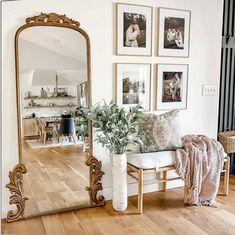 a mirror sitting on top of a wooden floor next to a white couch and potted plant