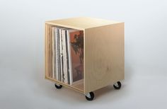 a wooden box with wheels holding various records and cds on it's sides, against a white background