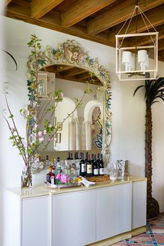 a bar with bottles and glasses on top of it next to a potted plant