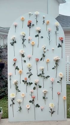 flowers are arranged on the side of a white wall in front of a house,