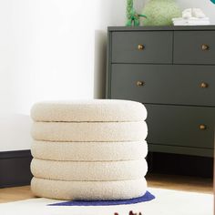 a stack of white towels sitting on top of a blue rug next to a dresser