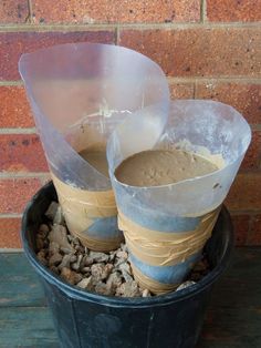 two buckets filled with sand next to a brick wall